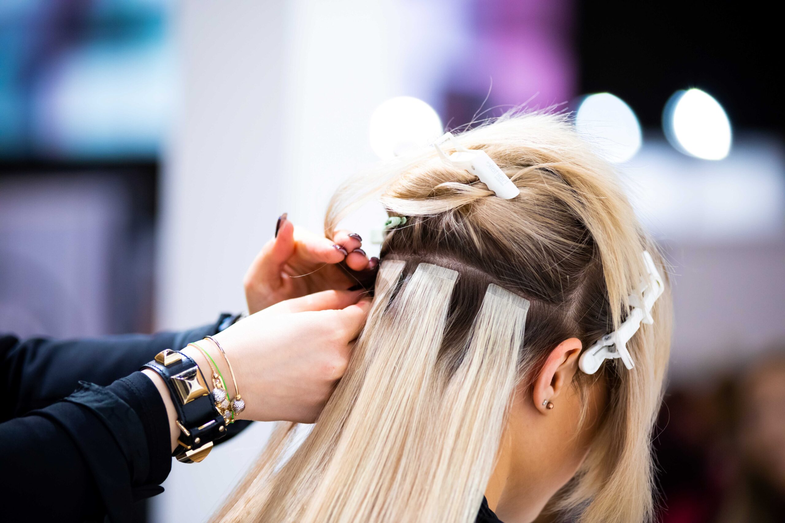 Professioneller Friseur, der in einem Schönheitssalon Haarverlängerungen für blonde Mädchen anfertigt

