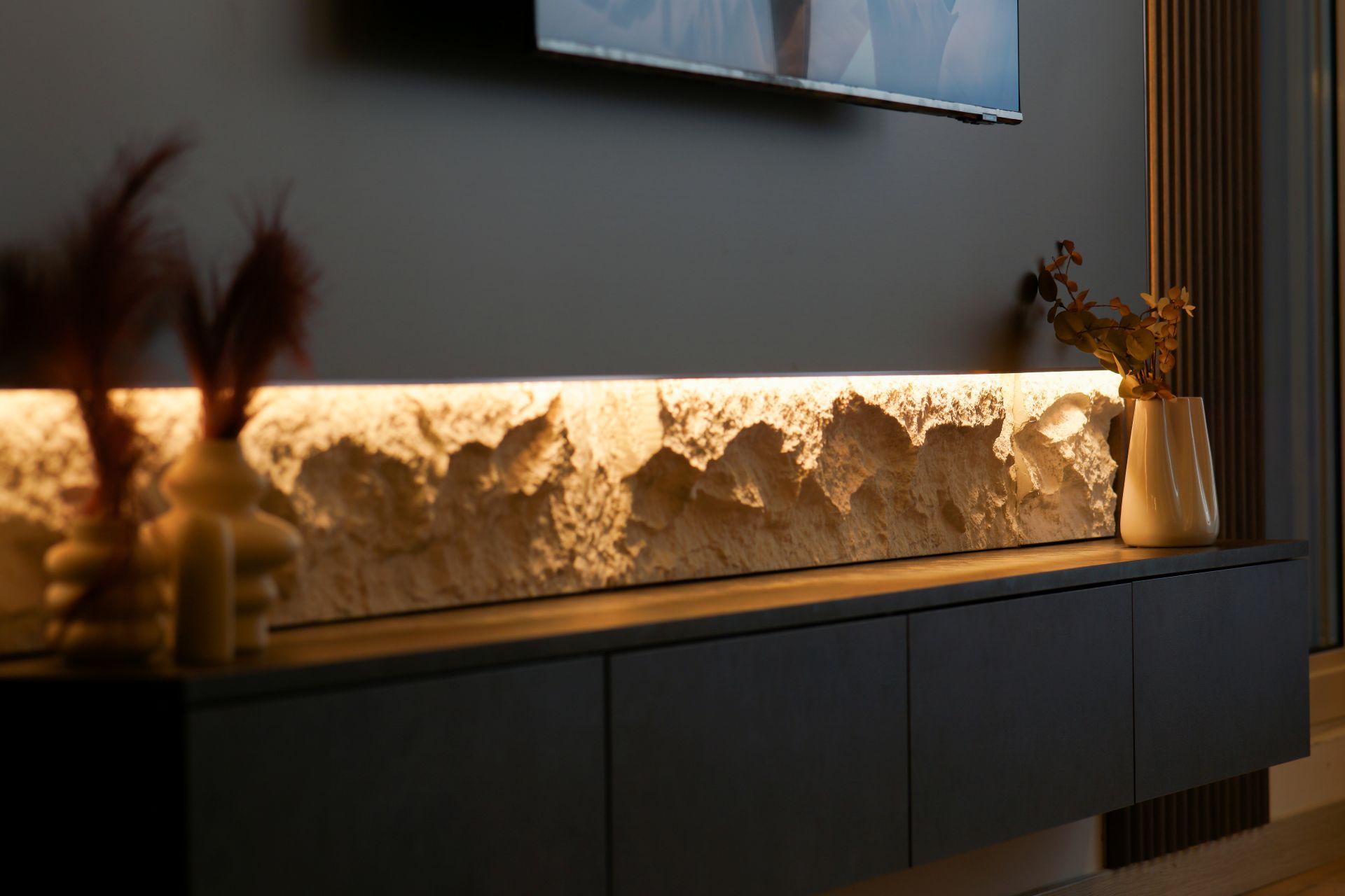 Wohnzimmer mit LED Strip als indirektes Licht hinter Steinleiste unter dem Fernseher – stilvolle DIY-Loesung fuer Wohnbereiche